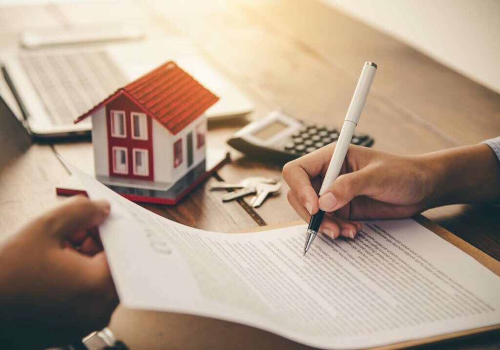 hand signing lease document on desk